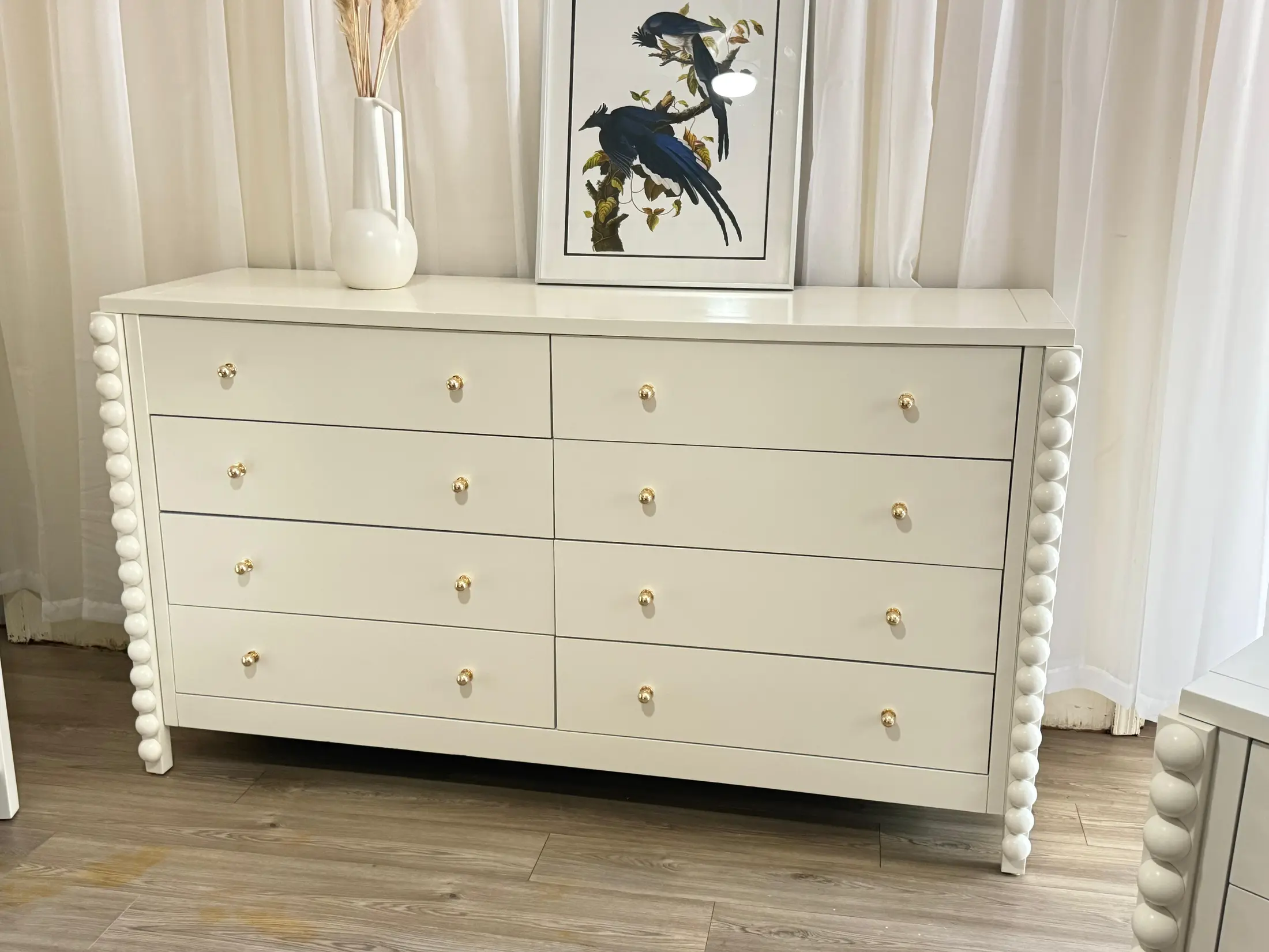 White dresser with sculptural spindle details and brass knobs